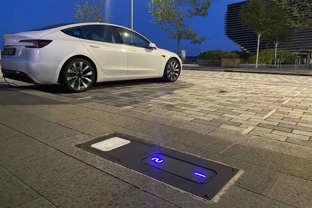 An electric car parked beside a retracted Urban Fox UEone chargepoint at dusk