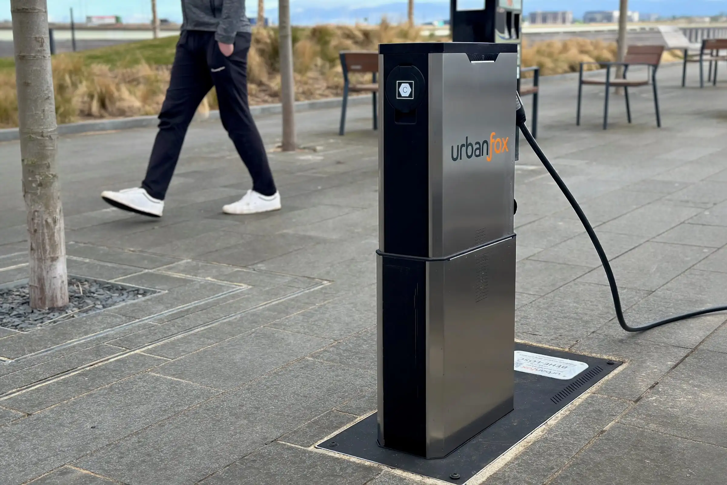 An Urban Fox chargepoint on a waterfront promenade as someone walks past